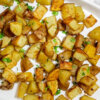 Plater of baked home fries garnished with fresh herbs.