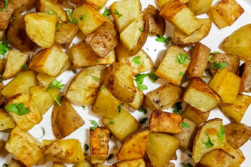 Plater of baked home fries garnished with fresh herbs.