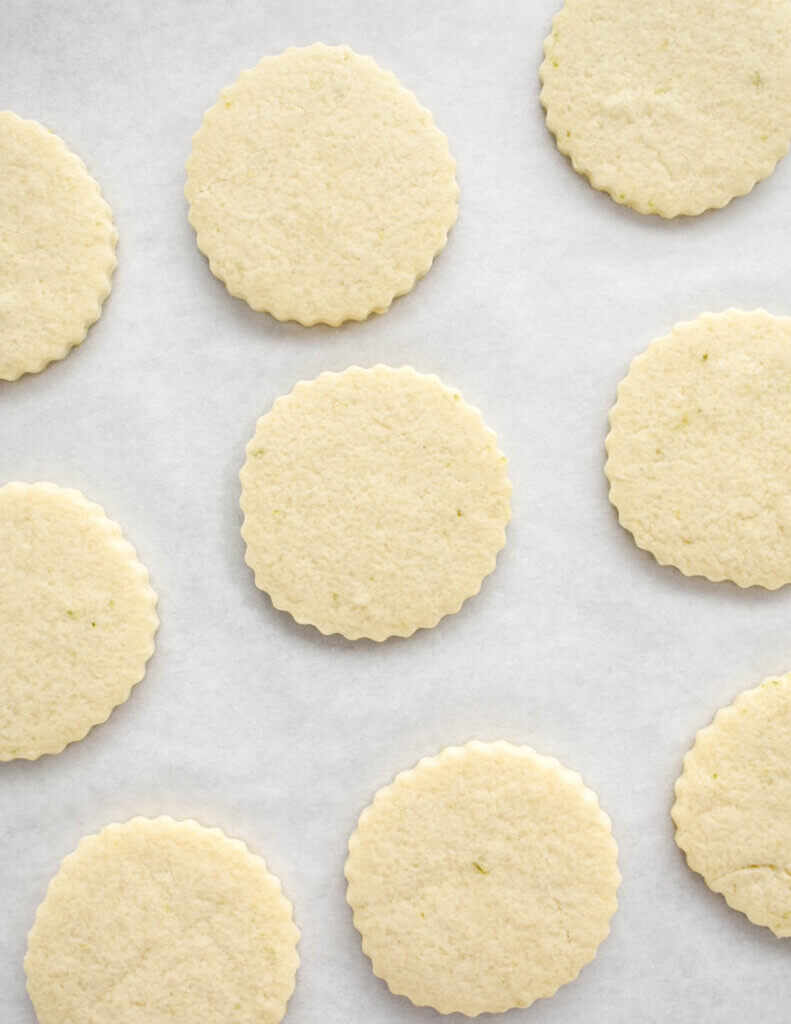 A parchment lined tray of baked round sugar cookies.