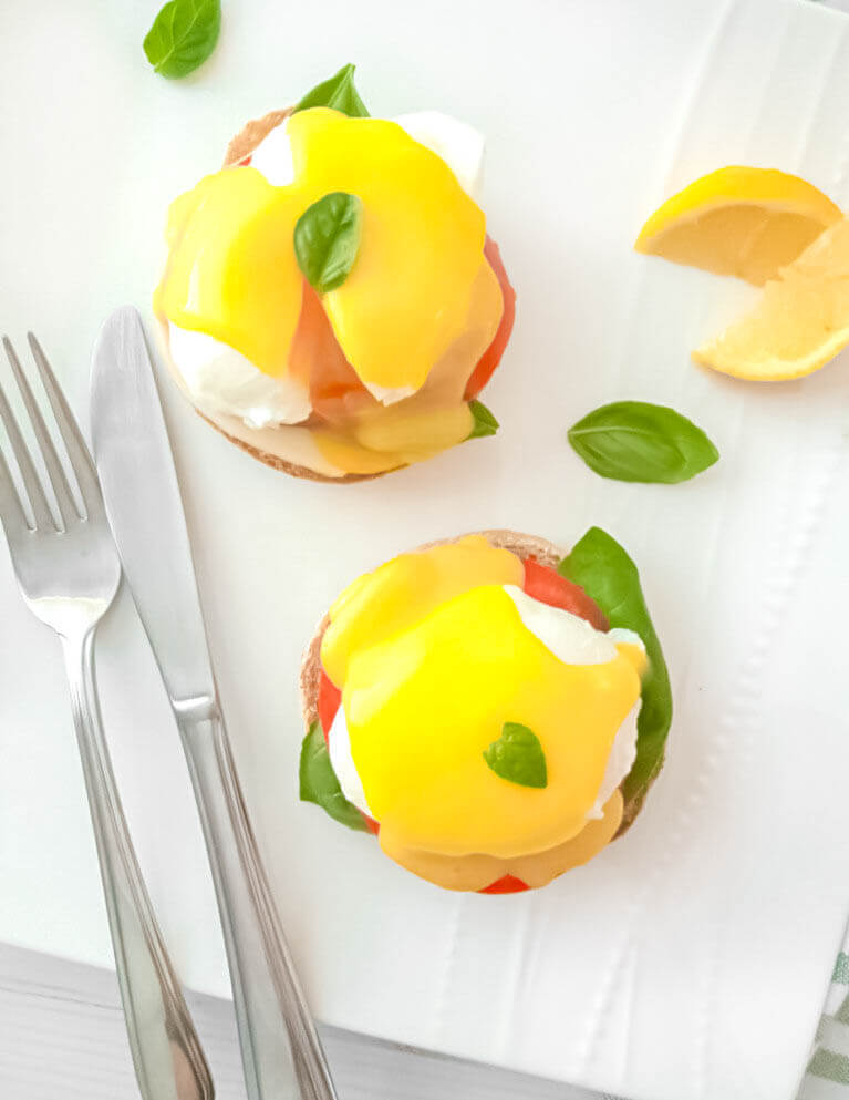 Poached eggs on english muffins with sliced tomato, fresh basil and hollandaise sauce.