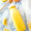 sunshine smoothie with peach lemon honey and turmeric in a juice bottle.