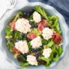 Blueberry, Prosciutto and Burrata Salad in a blue salad bowl.