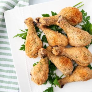 Baked Parmesan Chicken Drumsticks served on a bed of parsley.
