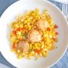 Healthy Corn and Red Pepper Salad with Seared Scallops on a white plate set on a blue napkin.
