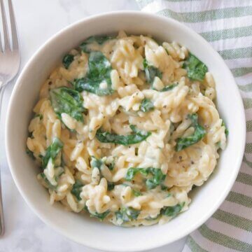 Bowl of Creamy Spinach Orzo set on a kitchen counter.