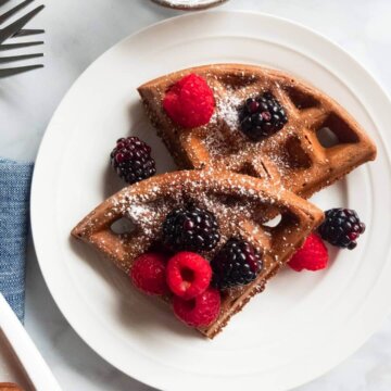 Plate of Healthy Dark Chocolate Waffles topped with icing sugar and fresh berries.