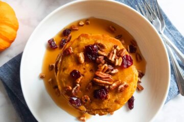 Topview of a stack of Healthy Pumpkin Pancakes covered in maple syrup and pecans.