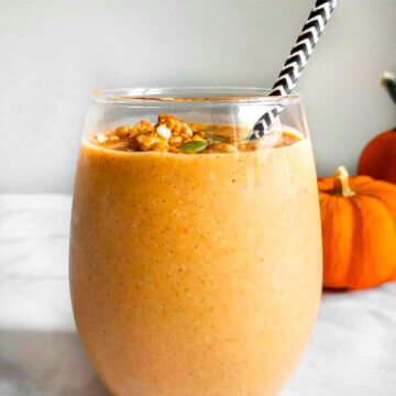 A cup of Pumpkin Pie Smoothie with a black and white striped straw.