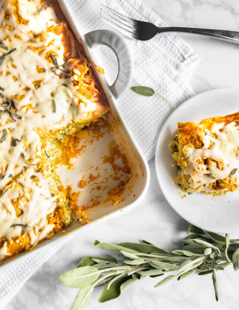 A baking pan with Pumpkin and Vegetable Lasagna with a slice removed and plated next to it.