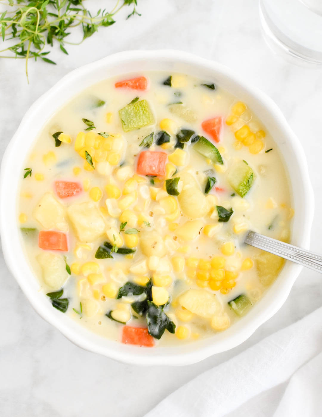 Closeup of a bowl of Summer Vegetable Chowder made with zucchini, carrots, corn, potatoes and spinach.