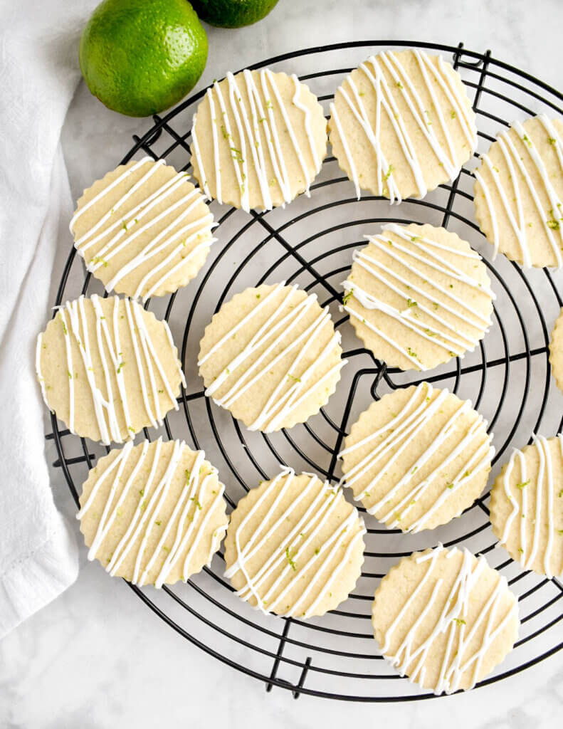 Freshly iced sugar cookies topped with royal icing in a zigzag pattern on a black cooling rack.
