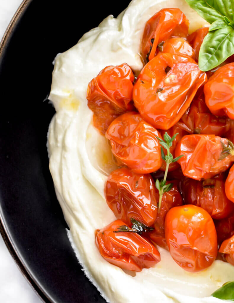 Closeup of creamy whipped feta dip topped with roasted grape tomatoes.