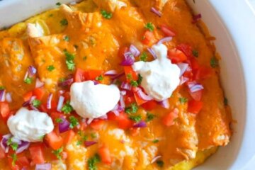 Breakfast Enchiladas topped with melted cheese, chopped tomatoes and sour cream.