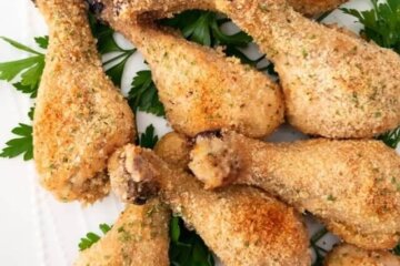 Baked Parmesan Chicken Drumsticks served on a bed of parsley.