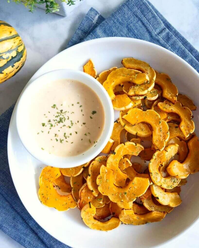 A bowl of Roasted Delicata Squash Fries with a creamy siracha dip.