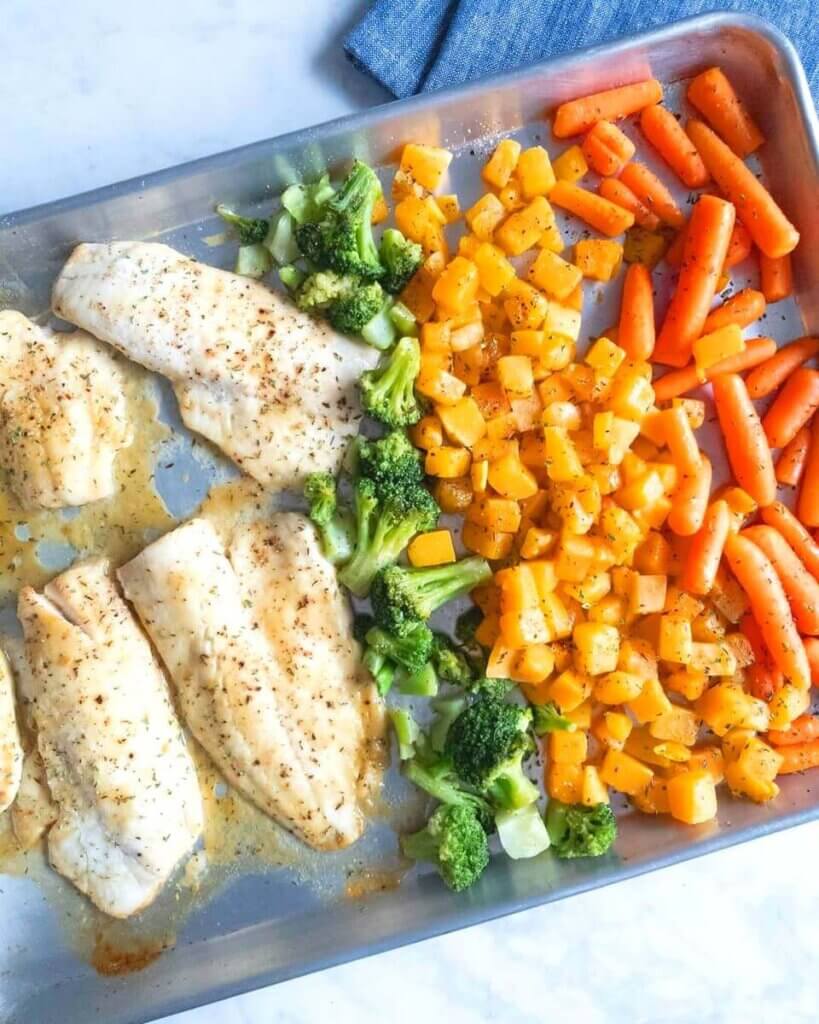 Sheet Pan Honey-Mustard Haddock and Roasted Vegetables set on a marble kitchen counter with a blue napkin.