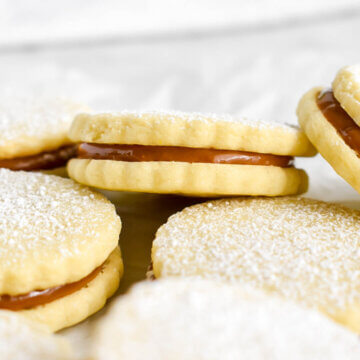 Close up of an alfajore showing the dulce de leche filling in a stack of cookies.