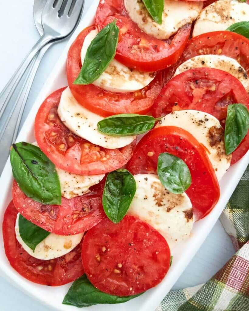 Caprese salad topped with fresh basil and drizzled with balsamic glaze.