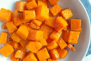A bowl of Simple Roasted Butternut Squash set on a blue napkin.
