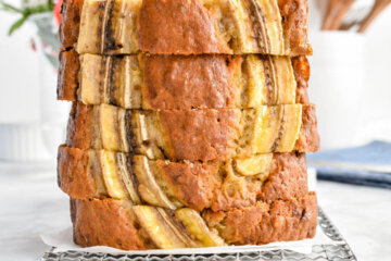Stacked slices of banana bread on a parchment lined cooling rack.