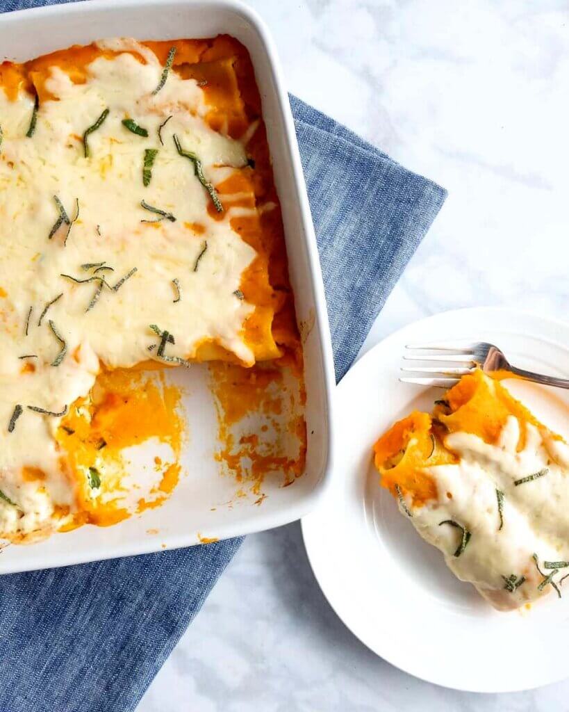 A baking dish of Creamy Squash, Spinach & Turkey Cannelloni next to a plated portion.