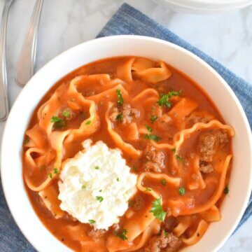 Bowl of Lasagna Soup topped with a dollop of ricotta cheeseset on a blue napkin