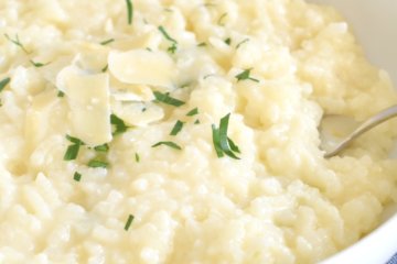 A plate of Parmesan Risotto sprinkled with parmesan cheese and herbs.