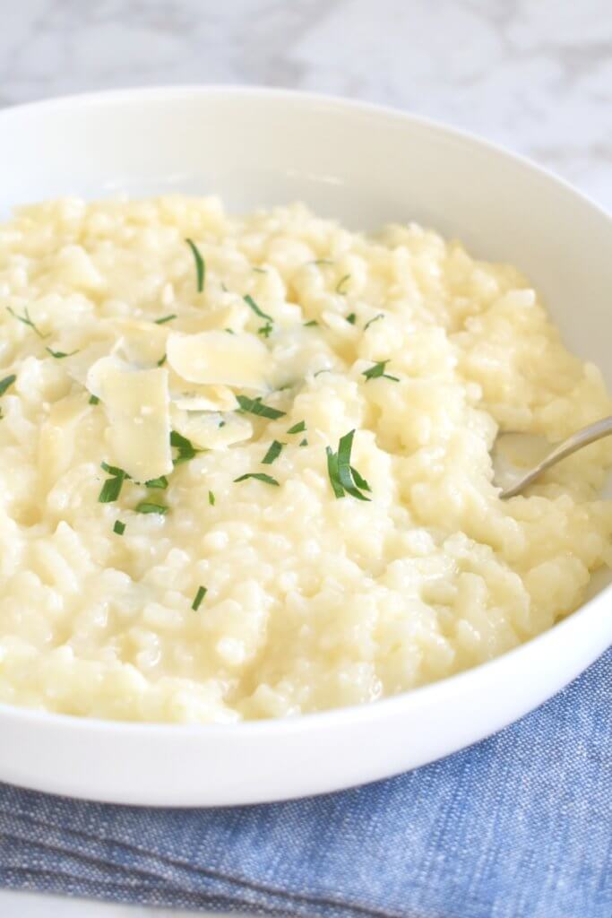 A plate of Parmesan Risotto sprinkled with parmesan cheese and herbs.