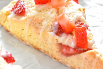 Closeup of a Strawberry Scone topped with fresh, chopped strawberries and drizzled with icing.