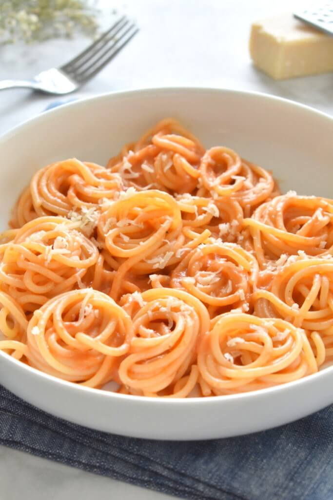 healthy roasted red pepper alfredo pasta plated with parmesan cheese.