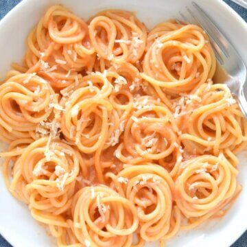 healthy roasted red pepper alfredo pasta twirls on a plate.