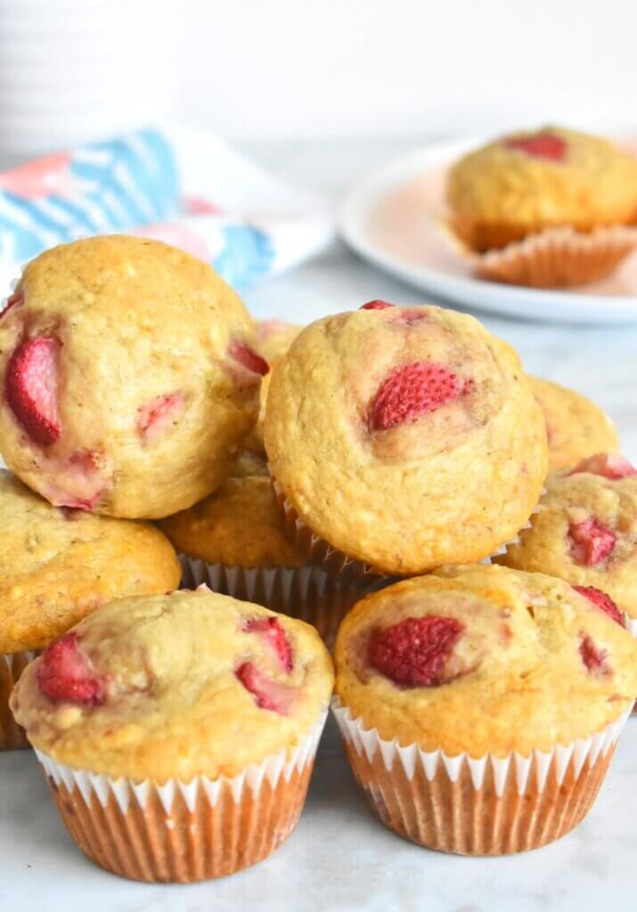 A pile of Healthy Strawberry Banana Muffins on a kitchen counter.