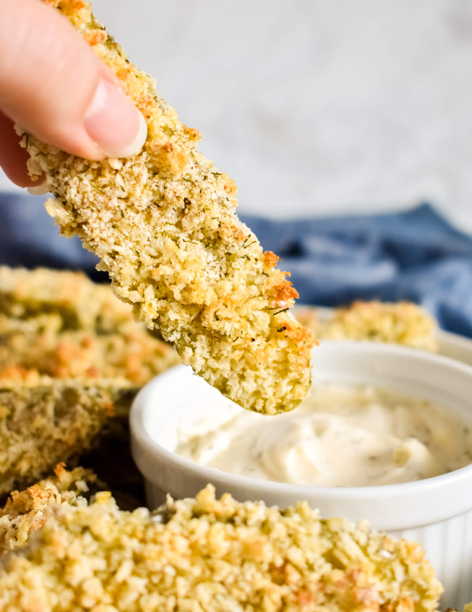 An Oven Fried Pickle being dipped in a creamy ranch dip.