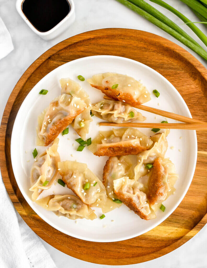 A plate of pork pot stickers with crispy golden bottoms.
