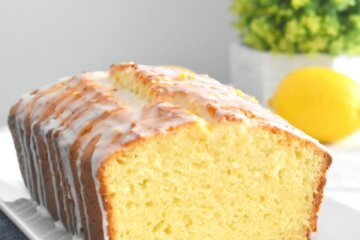 A sliced Lemon Ricotta Cake with icing drizzled over it on a rectangular platter.