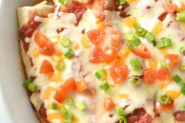 Baked Chicken Enchiladas topped with melted cheese, tomatoes and green onions.