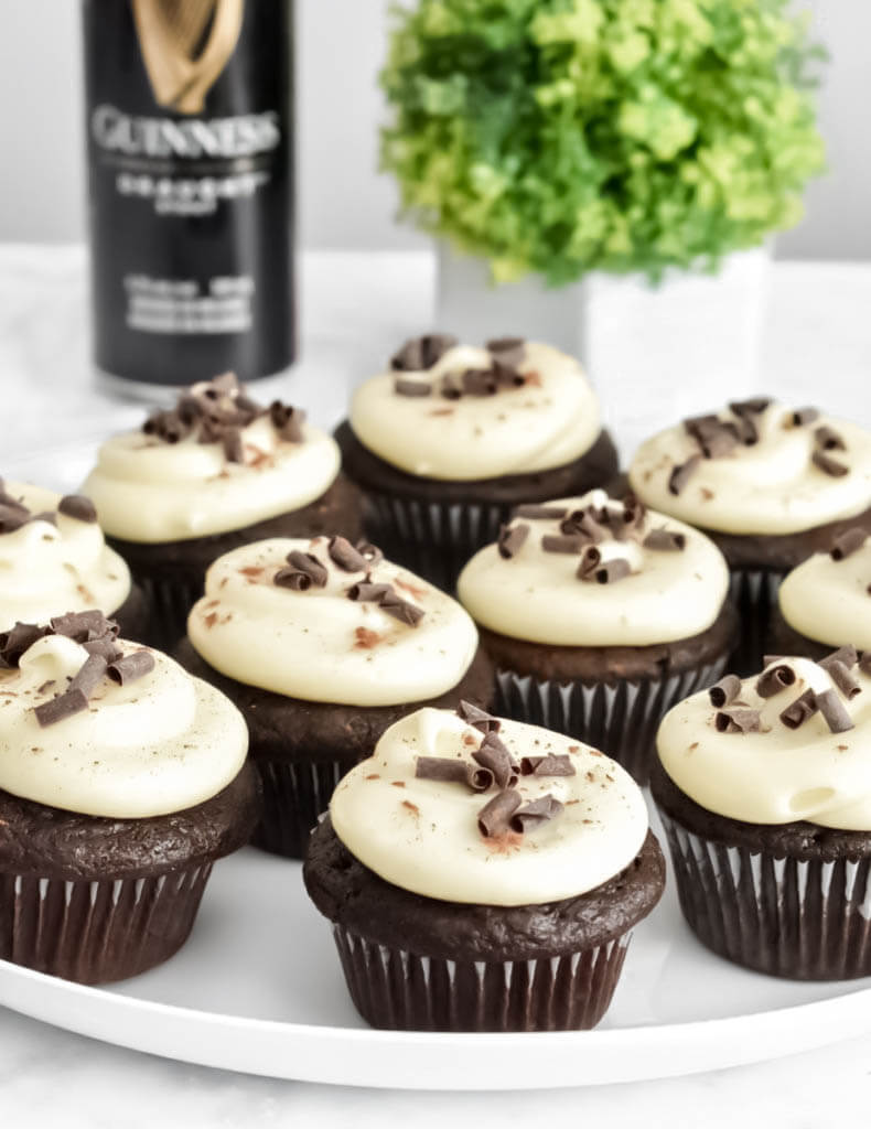 A platter of Chocolate Guinness Cupcakes with Cream Cheese Frosting next to a can of guinness beer.