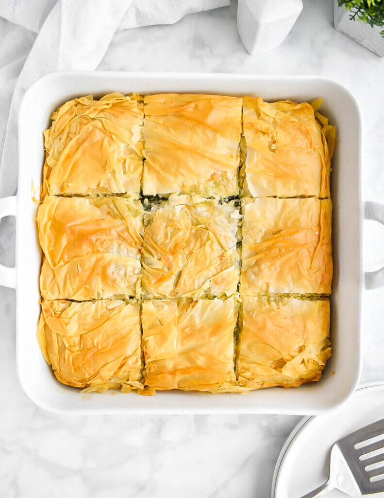 A square tray of golden brown spanakopita freshly baked.