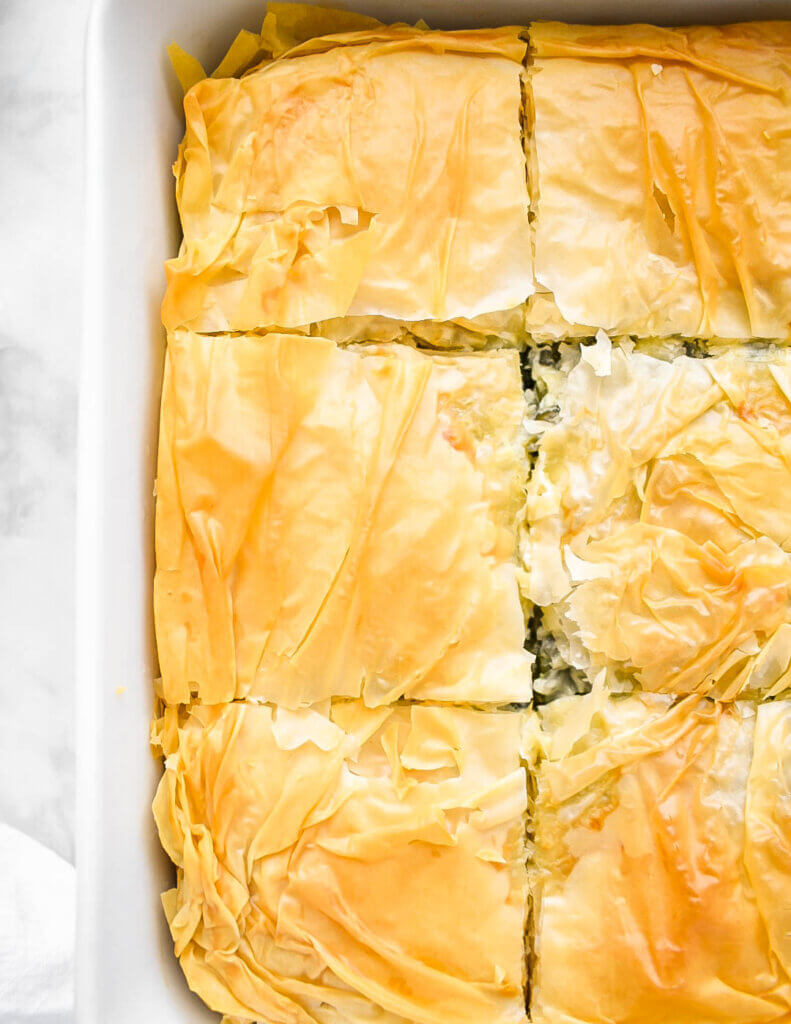 Closeup of the golden filo layers on top of a baked spanakopita.