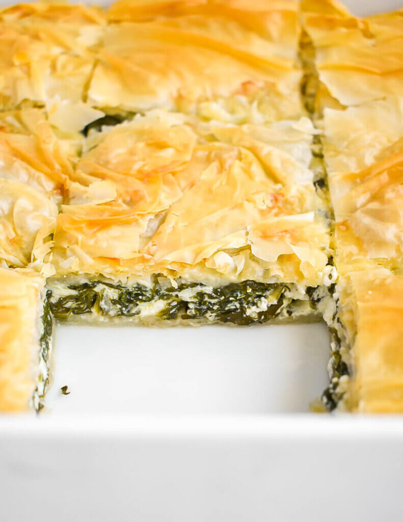 Closeup of cut slices of spanakopita in a pan.