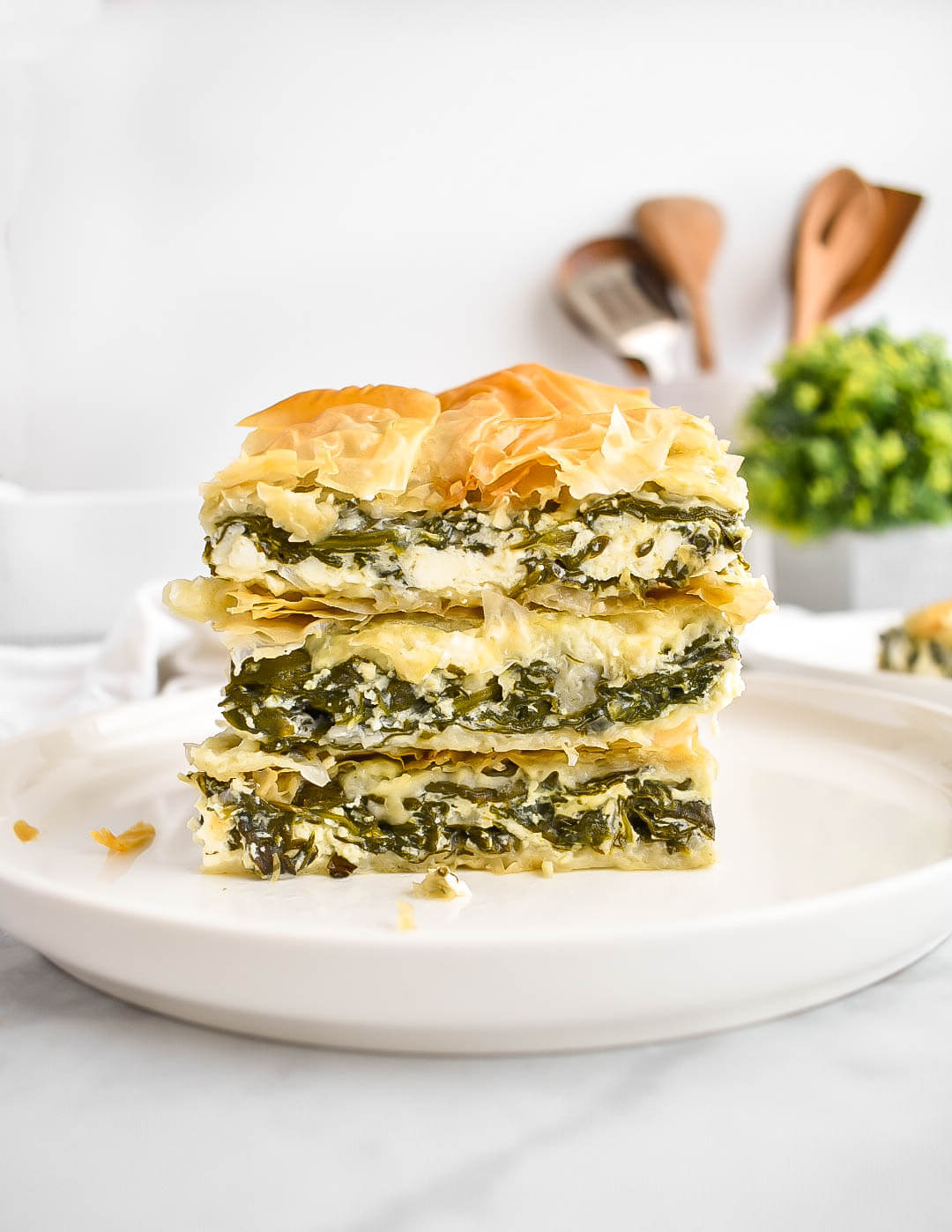 3 stacked slices of spanakopita on a plate.