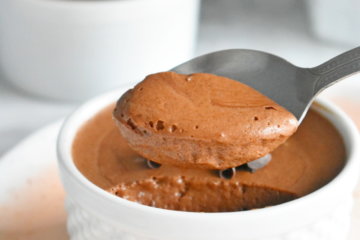 A spoon scooping some healthy chocolate mousse from a ramekin.