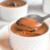 A spoon scooping some healthy aquafaba chocolate mousse from a ramekin.