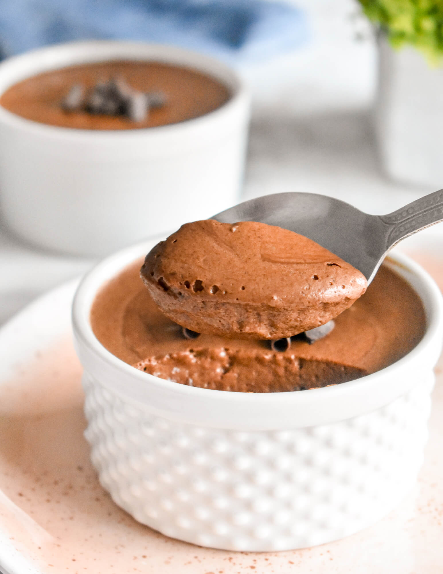 A spoon scooping some healthy aquafaba chocolate mousse from a ramekin.