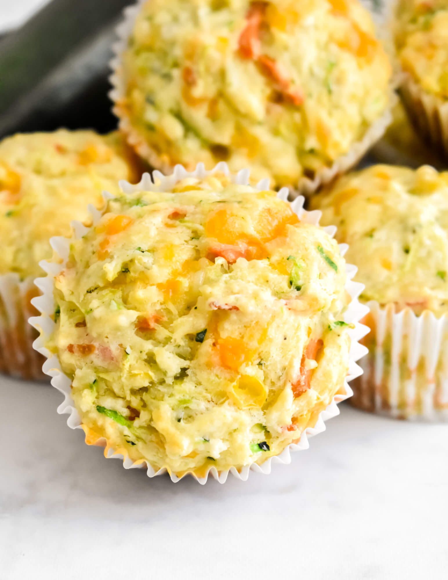 Closeup of a Savory Veggie Muffin showing the grated zucchini, carrots, and cheese.