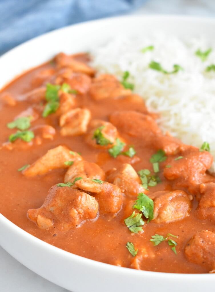 Butter chicken with lots of sauce sprinkled with fresh cilantro.