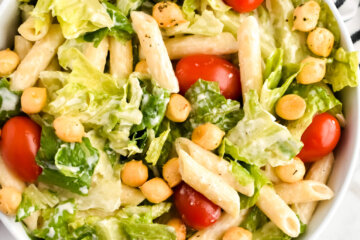 A bowl of Healthy Caesar Pasta Salad topped with cherry tomatoes and croutons.