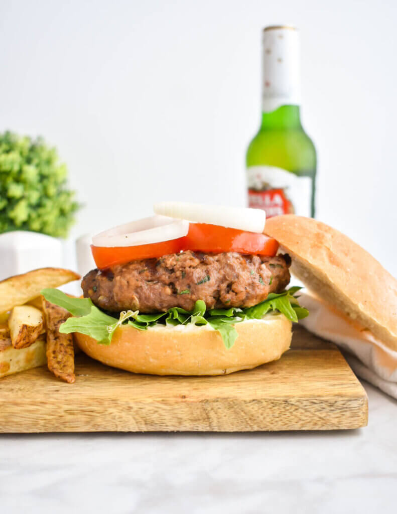 A hamburger and fries set on a wooden cutting board.