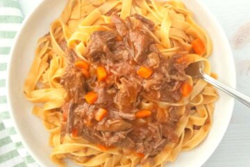 A bowl of pasta topped with Pressure Cooker Beef Ragu.