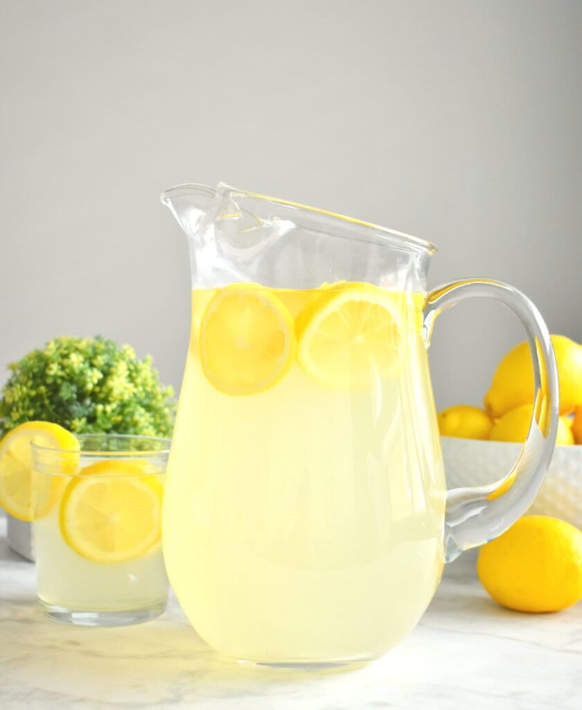 A pitcher of lemonade with  lemon slices.